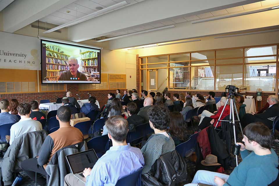 A room of people watching a presentation on a screen