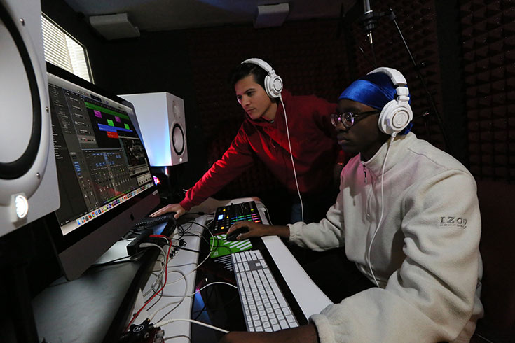Two students wearing headphones working in a sound studio