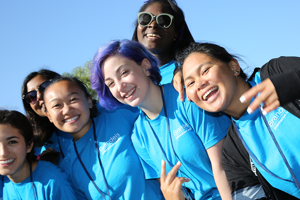 Brandeis students in blue orientation T-shirts smile and horse around for the camera