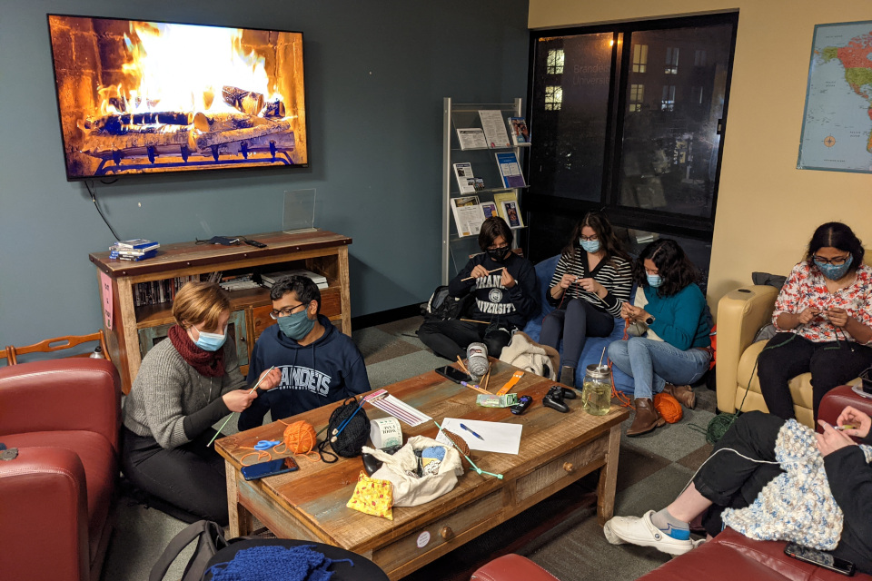 Six knitters sit on the floor and in bean bags, intently focused on their projects