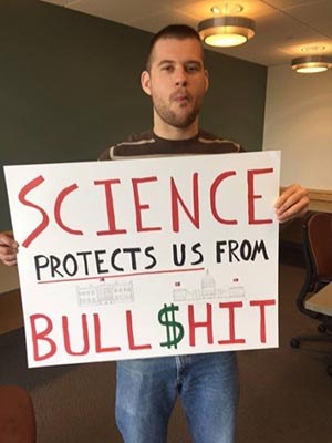 Student holding his poster that says: Science protects us from Bull$hit