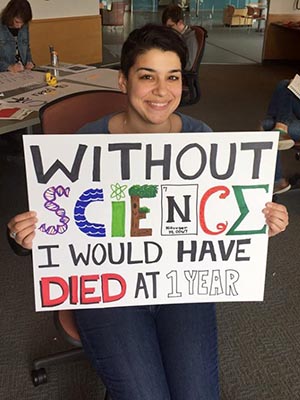 Student holding her poster which says: Without science I would have died at Year 1