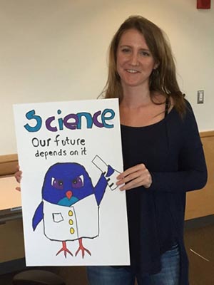 Student holding her poster which says Science: Our future depends on it