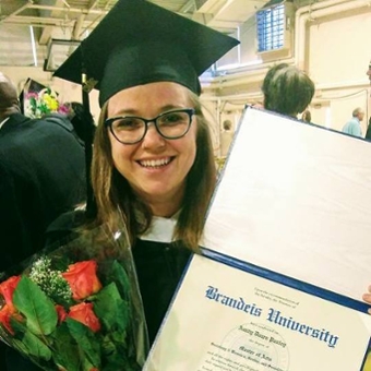 Amity Pauley, beaming in graduation cap and gown, holds up her diploma