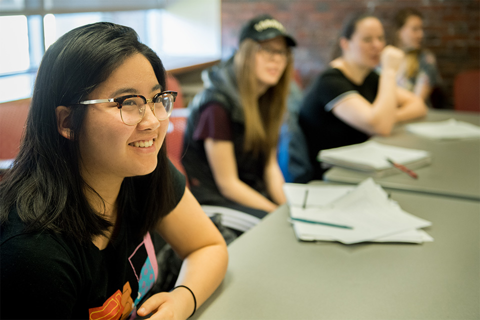 Smiling students seated at a long classroom table