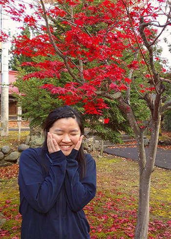 Teresa Fong expresses joy in front of bright red tree 
