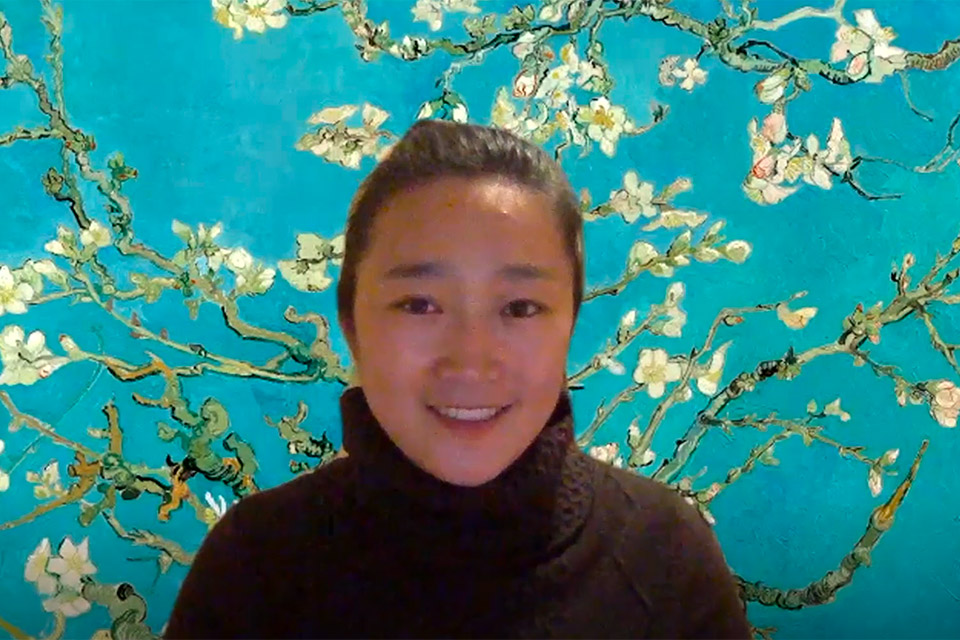 female professor in front of aqua-colored flowered wallpaper