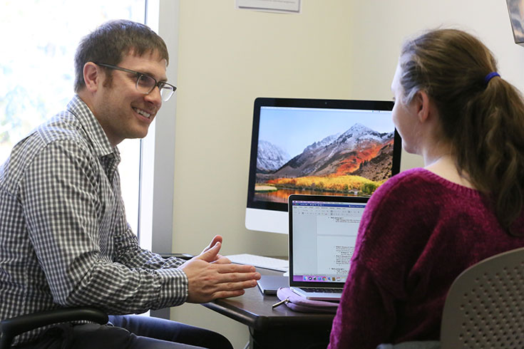 Two people work together on computers at the Writing Center