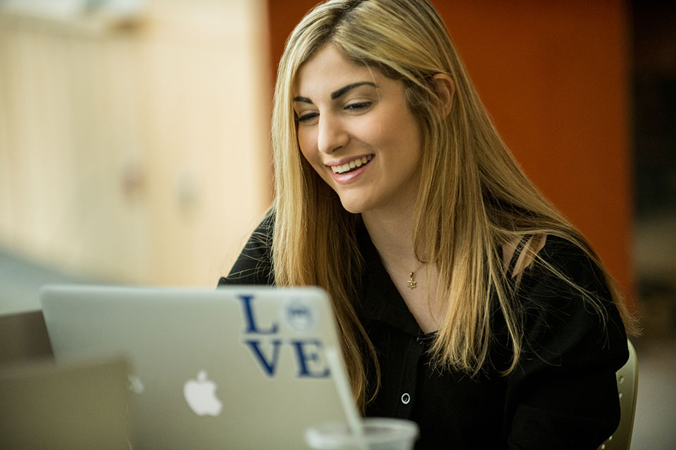 Student smiling while working on a laptop
