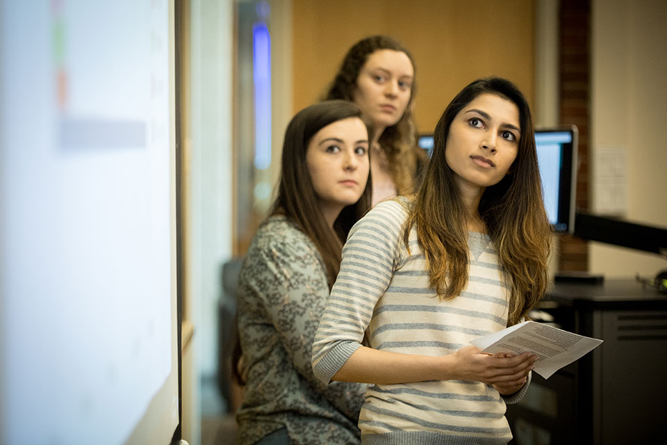 Group of students speaking in the front of a classroom