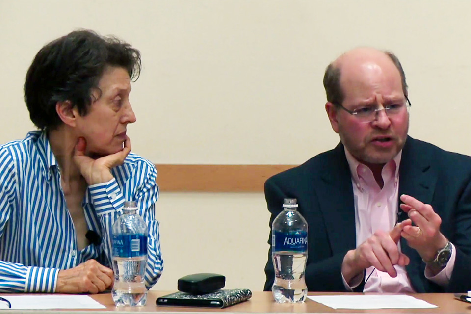 male and female professor engaged in discussion at table