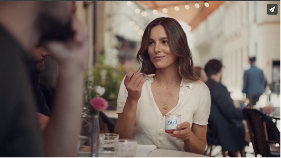 A young woman eats yogurt at a French cafe