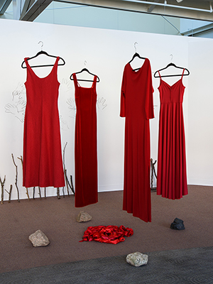 installation view Jaime Black exhibition, 4 red dresses hanging with photos in the background