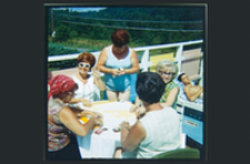 A roup of women sitting around white table on boat playing cards