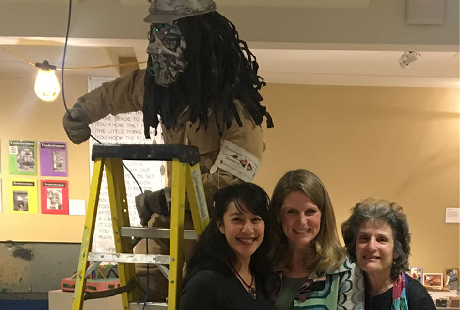 "Stella" figure on ladder in art gallery with three women