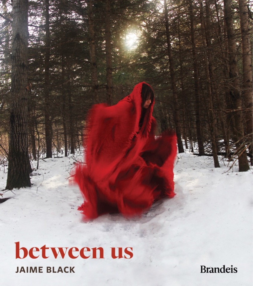 A person dressed in red runs in a snowy forest.