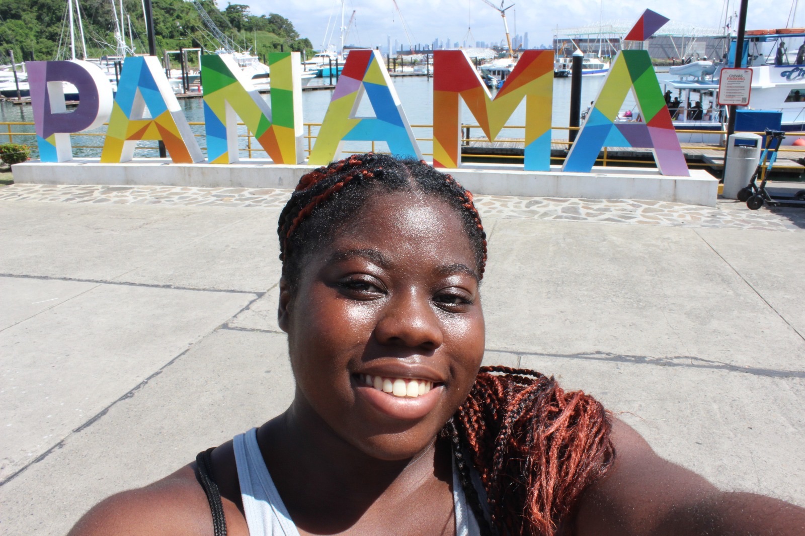 Ianna stands smiling in front of multicolored letter sculptures that spell Panama.