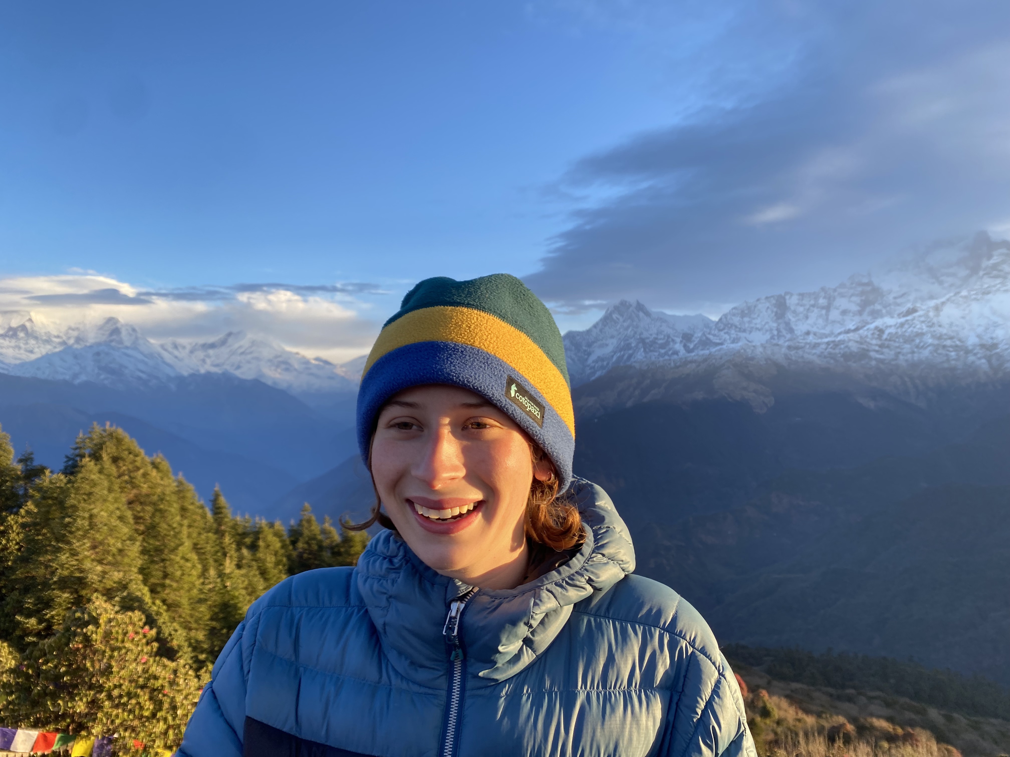 A close-up of Caroline smiling in a winter hat on a mountain in Nepal.