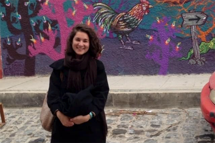 A Brandeis alumna stands in front of a painted wall