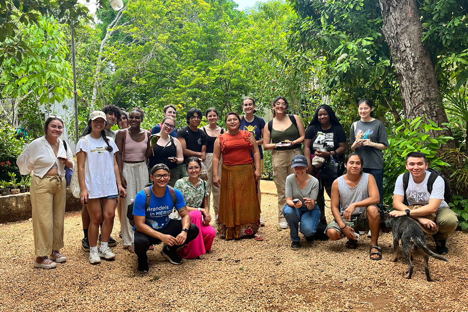 A group of Brandeis students in a forest setting with a local healthcare provider
