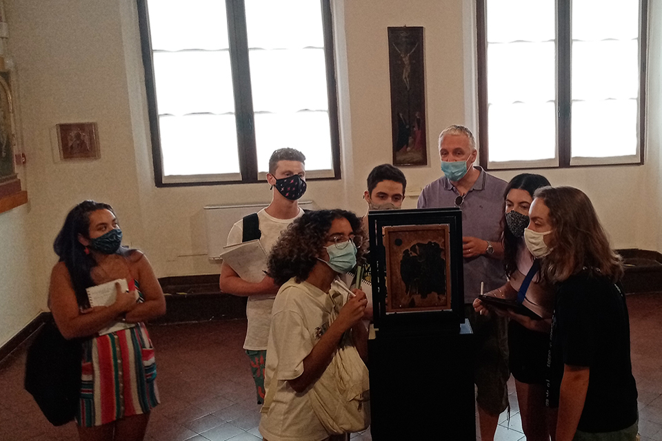 Students surrounding a painting in an Italian museum accompanied by Professor Roberto Fineschi