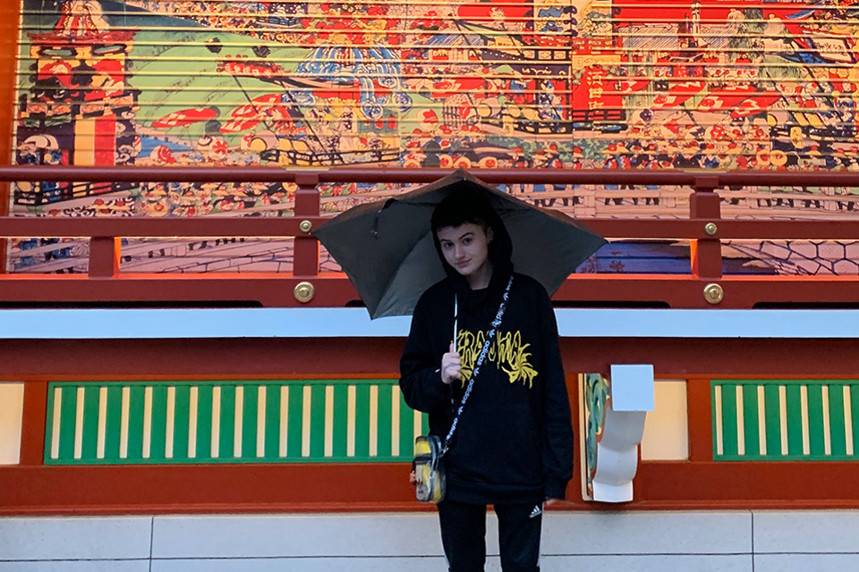 A student with an umbrella in front of a colorful wall