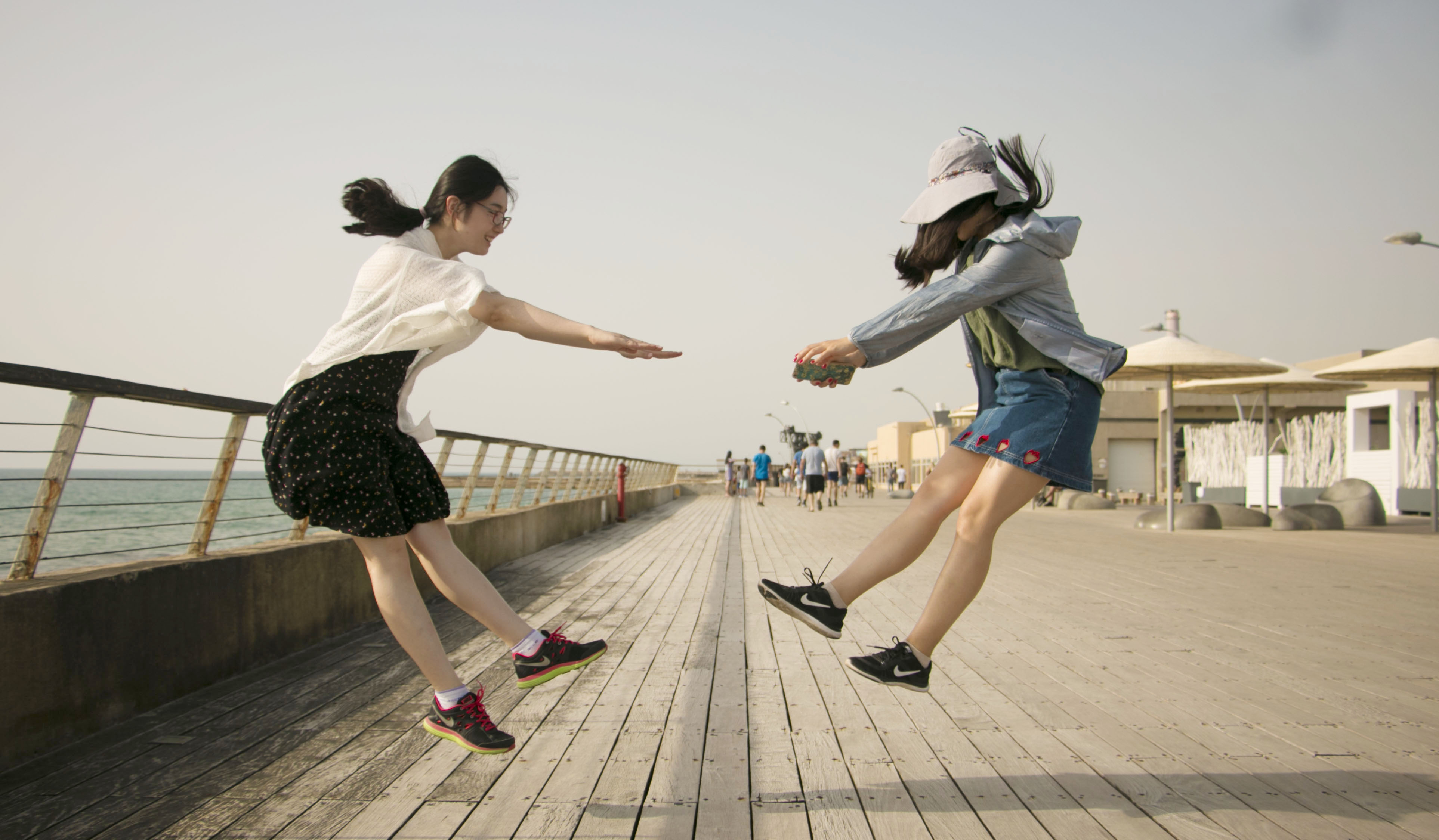 Two students jumping along the boardwalk.