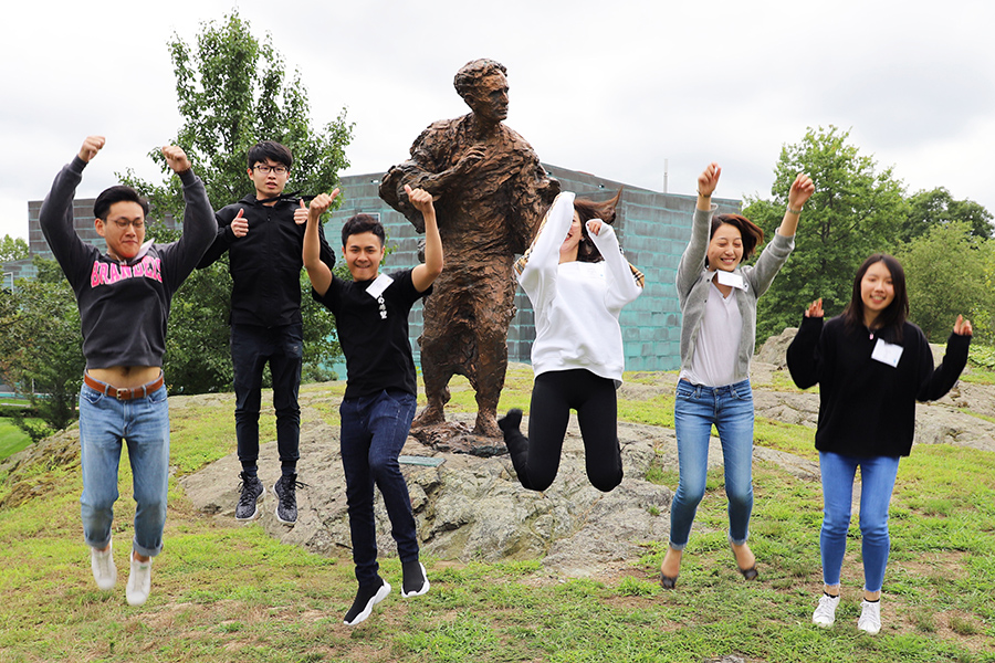 Students jump in front of a statue.