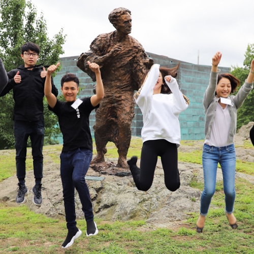Students jumping in front of a statue.