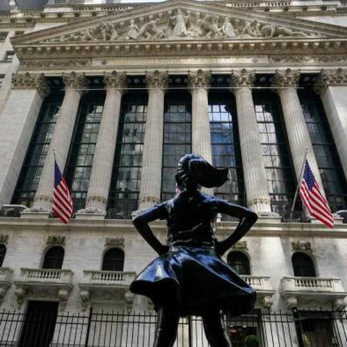 A photo of the Fearless Girl statue staring down the facade of the New York Stock Exchange.