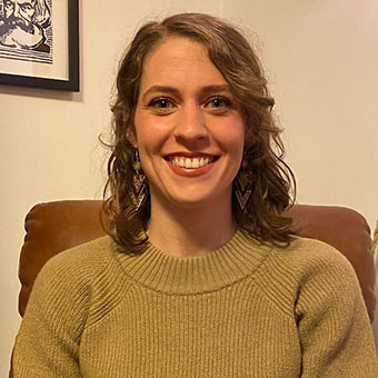 Rachel Dale sits in a chair next to a bookshelf