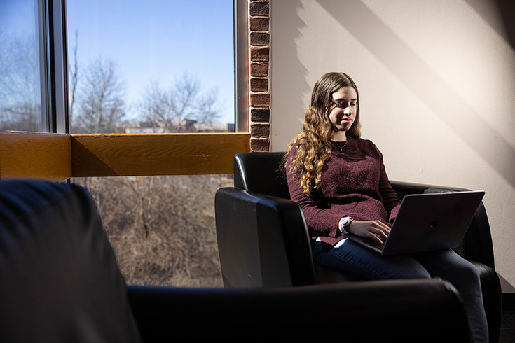 Aviva Weinstein '23 poses for a photo in the library at Brandeis University on March 20, 2023. Photo/Dan Holmes