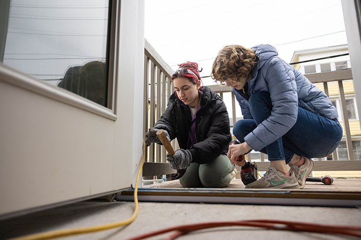 Brandeis student Esther Daube-Valois ‘23, left, and Savannah Johnson ‘23 volunteer at a Habitat for Humanity project in Lawrence on April 22, 2023. Photo/Dan Holmes