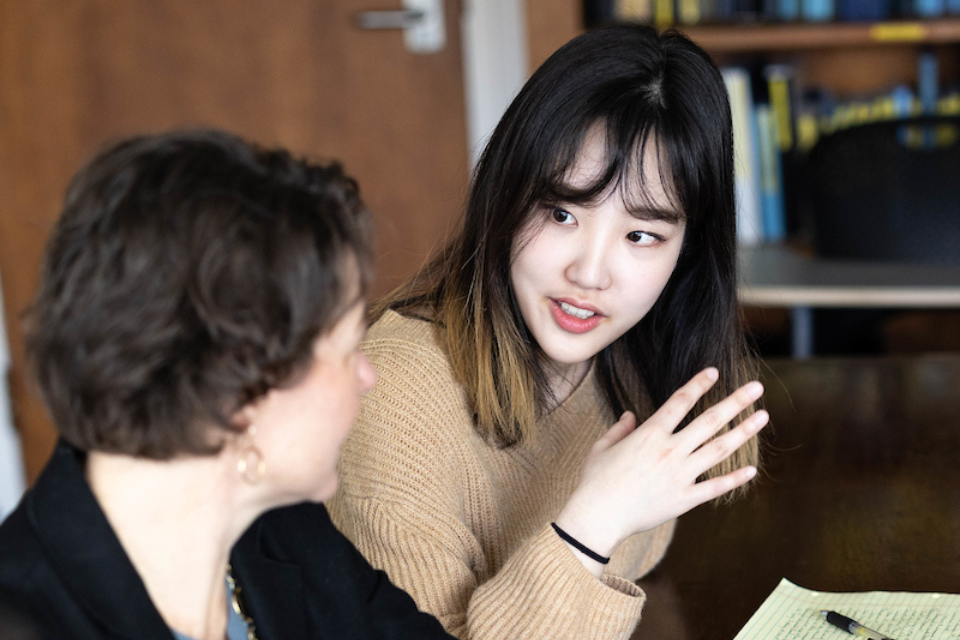 Student speaks to professor in classroom.