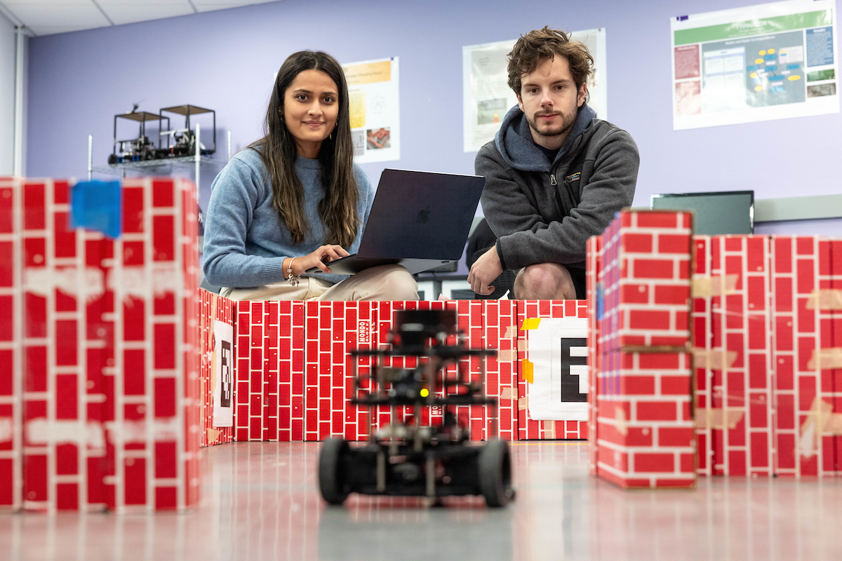 Two students power robotic device in class.