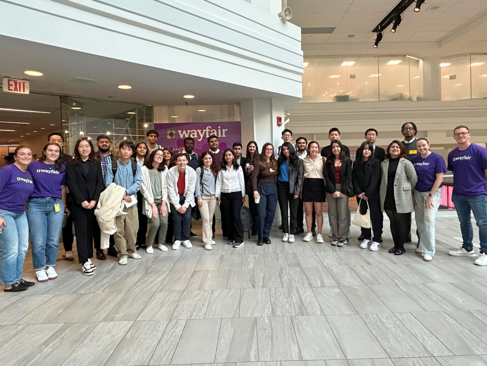 Visiting Brandeis students and Wayfair team members stand in front of Wayfair office sign.