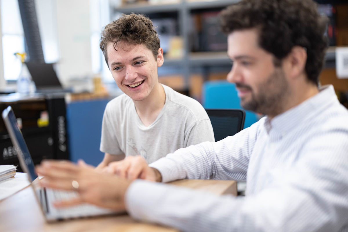 Student works on laptop with faculty member.