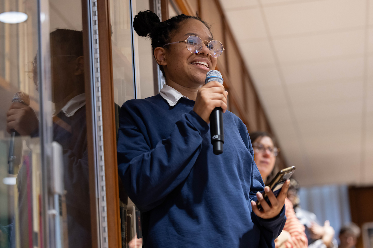 Journalism student speaks into microphone at event.