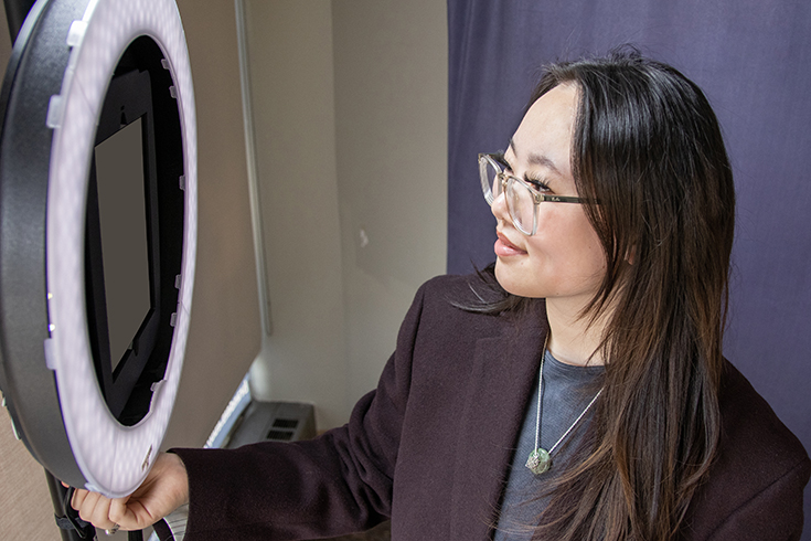 A student adjusts the lighting of Hiatt's LinkedIn Photo Booth.