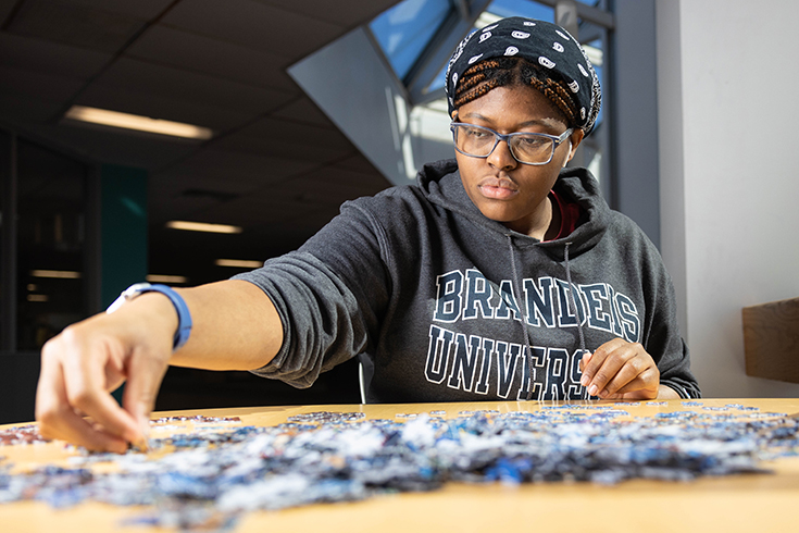 Gabrielle Daley ‘26 works on a puzzle in the Goldfarb Library at Brandeis University on March 20, 2023. Photo/Dan Holmes