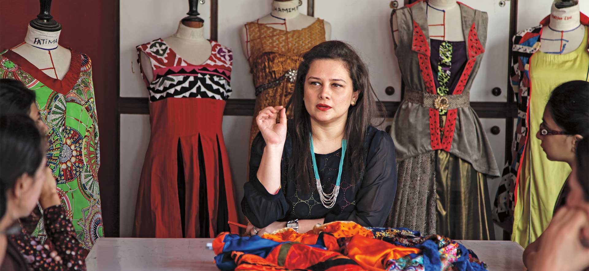 Ambreen Khan sits among clothing designs in a meeting