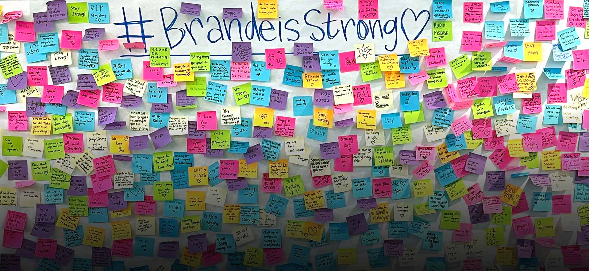 The hashtag Brandeis Strong with a heart is written at the top of a large poster-sized paper. There are many colorful post-it notes stuck on the paper with supportive messages from community members.