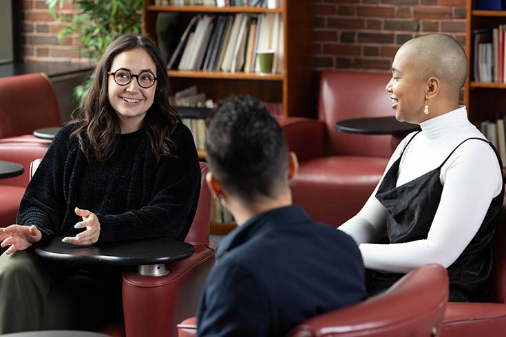 Heller students smile while talking in an office