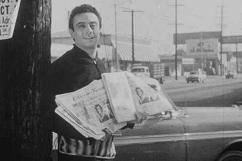 Black and white image of man holding newspapers