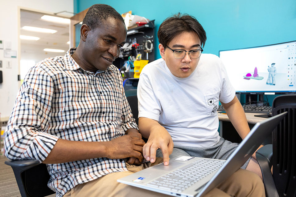 Two students look at a laptop in the MakerLab