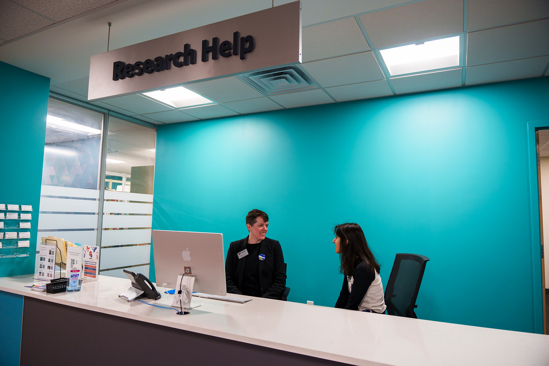 A librarian helps a patron at the Research Help desk