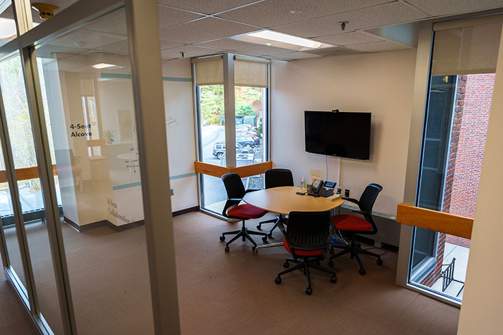 A room with lots of windows and four chairs around a table