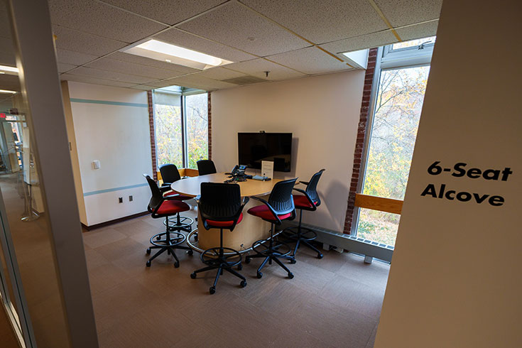 A room with lots of windows and a table with six chairs around it.