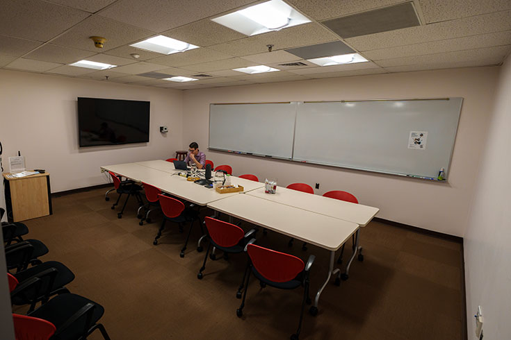 A large room with a long conference table, a white board, and a television