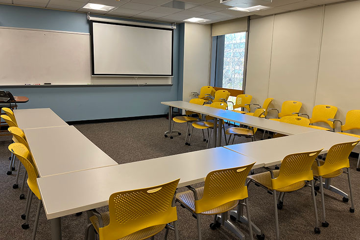 Desks and chairs in a U-shaped formation facing a large white board